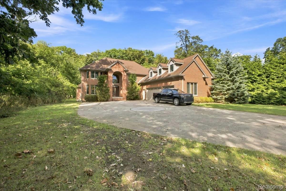 8610 Ferry Road Grosse Ile, MI 48138 - Photo 52 of 55 Brick exterior with multiple dormer windows, a prominent arched entry, and an attached multi-car garage