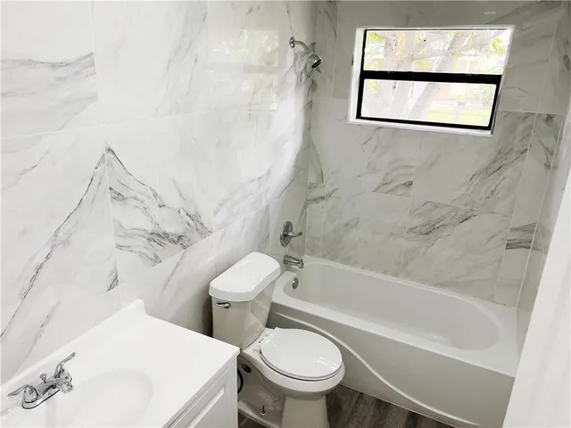 a white toilet sitting next to a bath tub and a shower