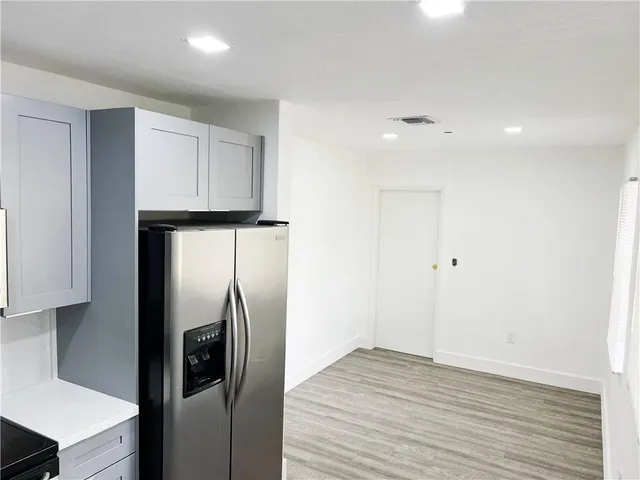 a view of a refrigerator in kitchen and an empty room
