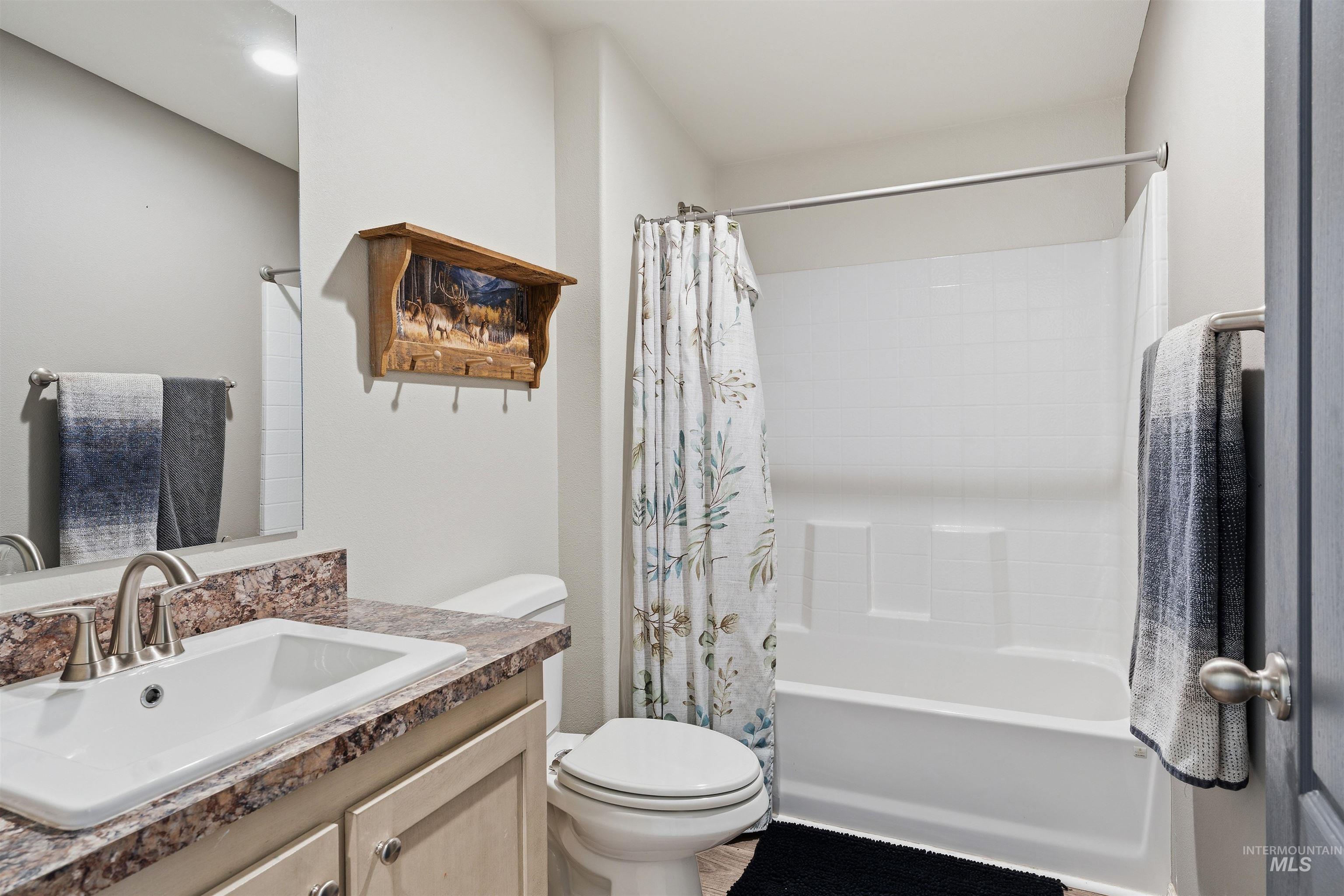 302 3rd Avenue Craigmont, ID 83523 - Photo 12 of 31 Bathroom featuring a vanity with an integrated sink and stone-finish countertop, a mirror, a toilet, and a combined tub and shower unit