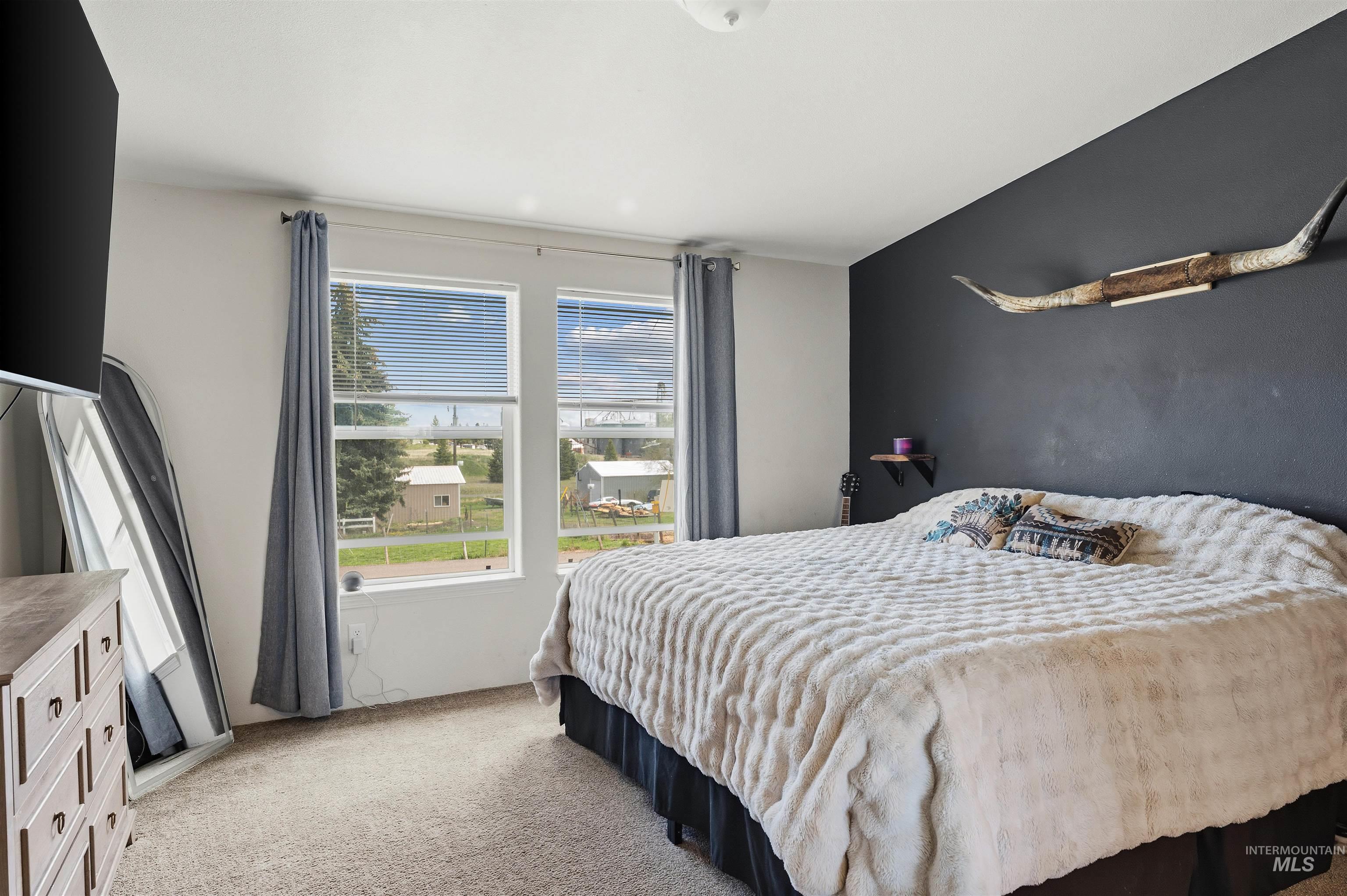 302 3rd Avenue Craigmont, ID 83523 - Photo 13 of 31 Carpeted bedroom featuring a dark accent wall, two large windows with blinds, and white trim
