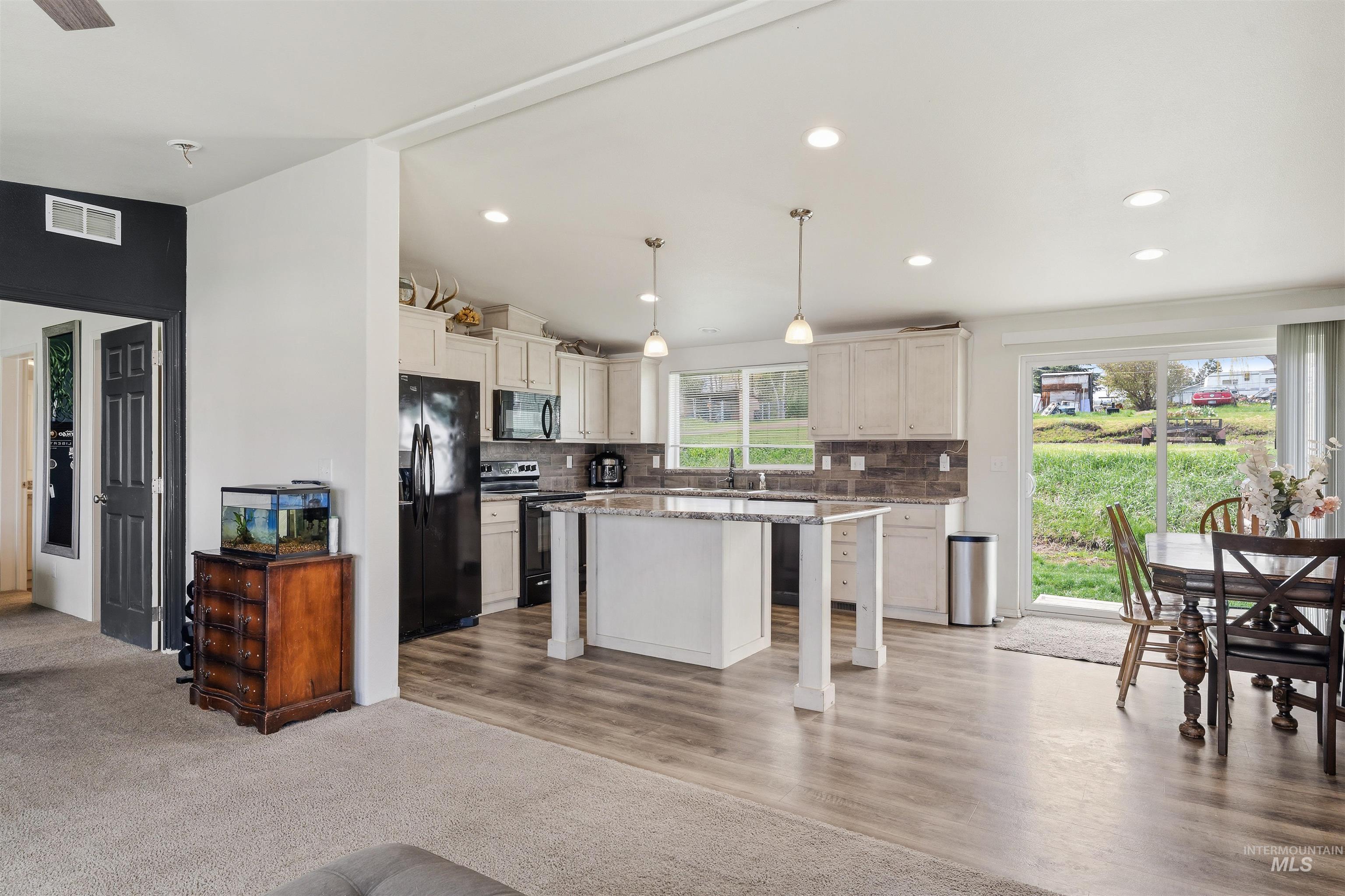 302 3rd Avenue Craigmont, ID 83523 - Photo 22 of 31 Open-concept kitchen with white cabinetry, dark subway tile backsplash, and a central island with a light-toned countertop