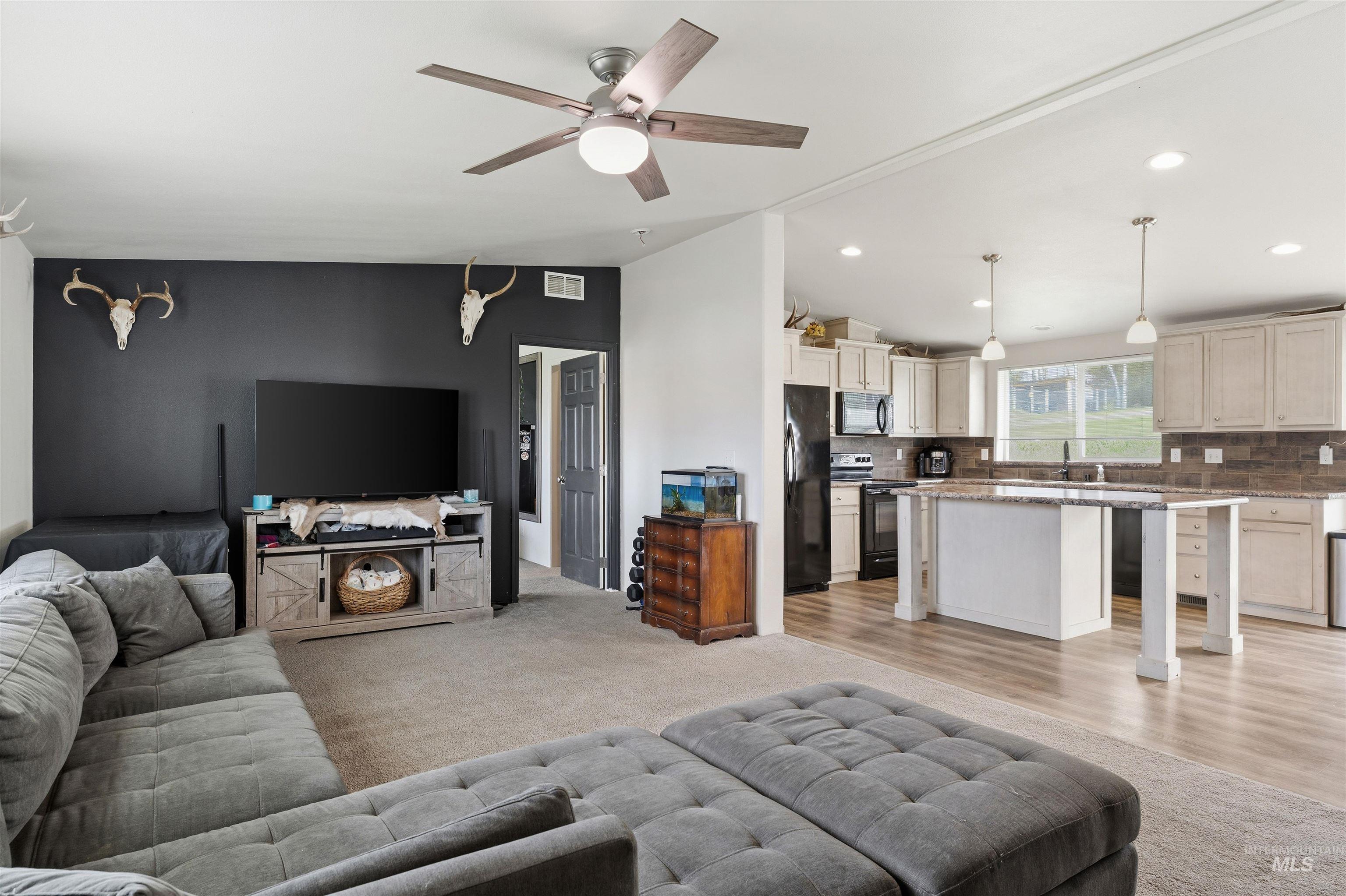 302 3rd Avenue Craigmont, ID 83523 - Photo 23 of 31 Open-concept living area featuring a ceiling fan with integrated lighting, a contrasting accent wall, and carpet flooring