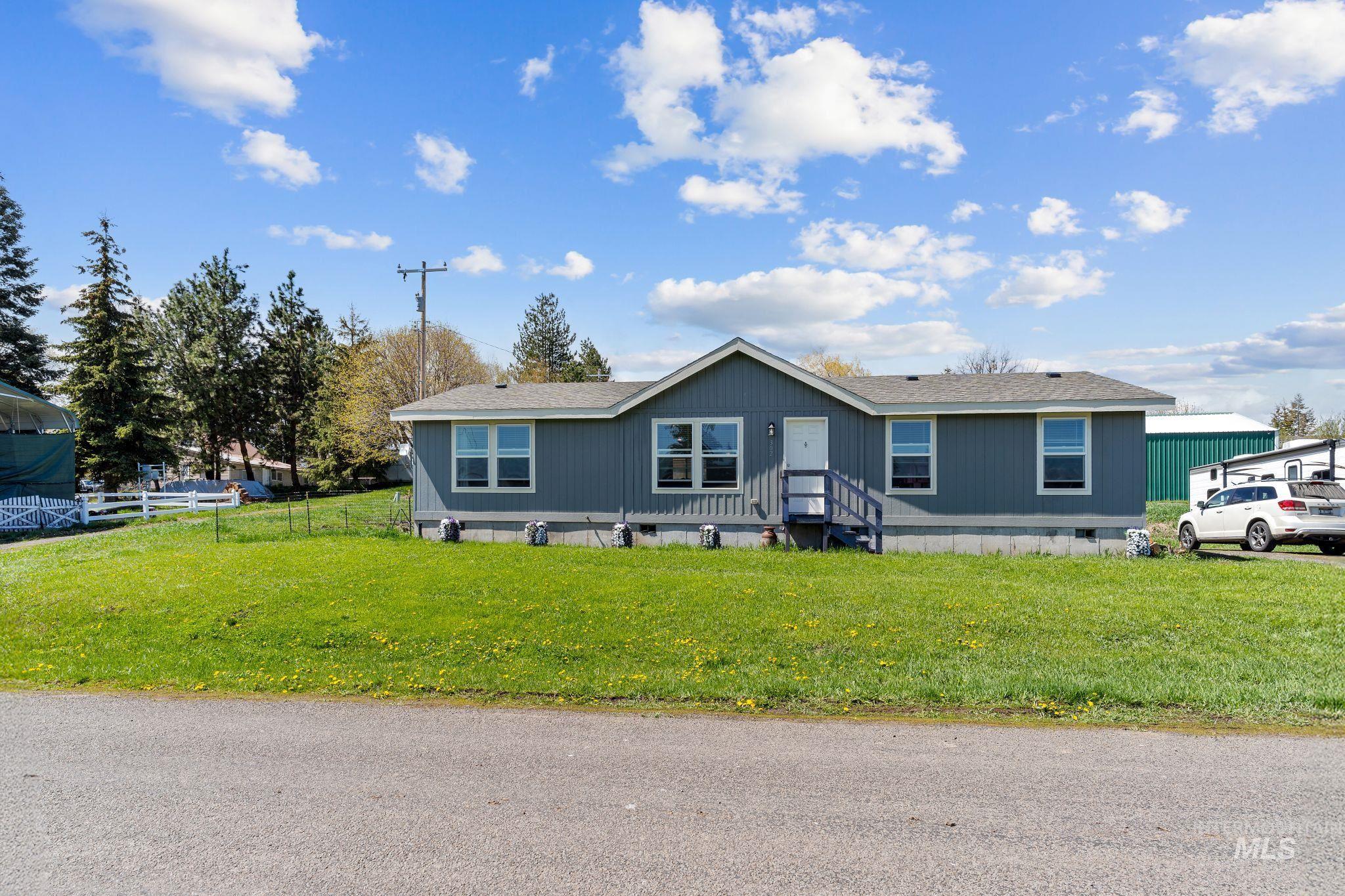 302 3rd Avenue Craigmont, ID 83523 - Photo 25 of 31 Single-story property featuring a gray exterior with white trim, a gabled roofline, multiple windows, and a front entry porch with blue steps