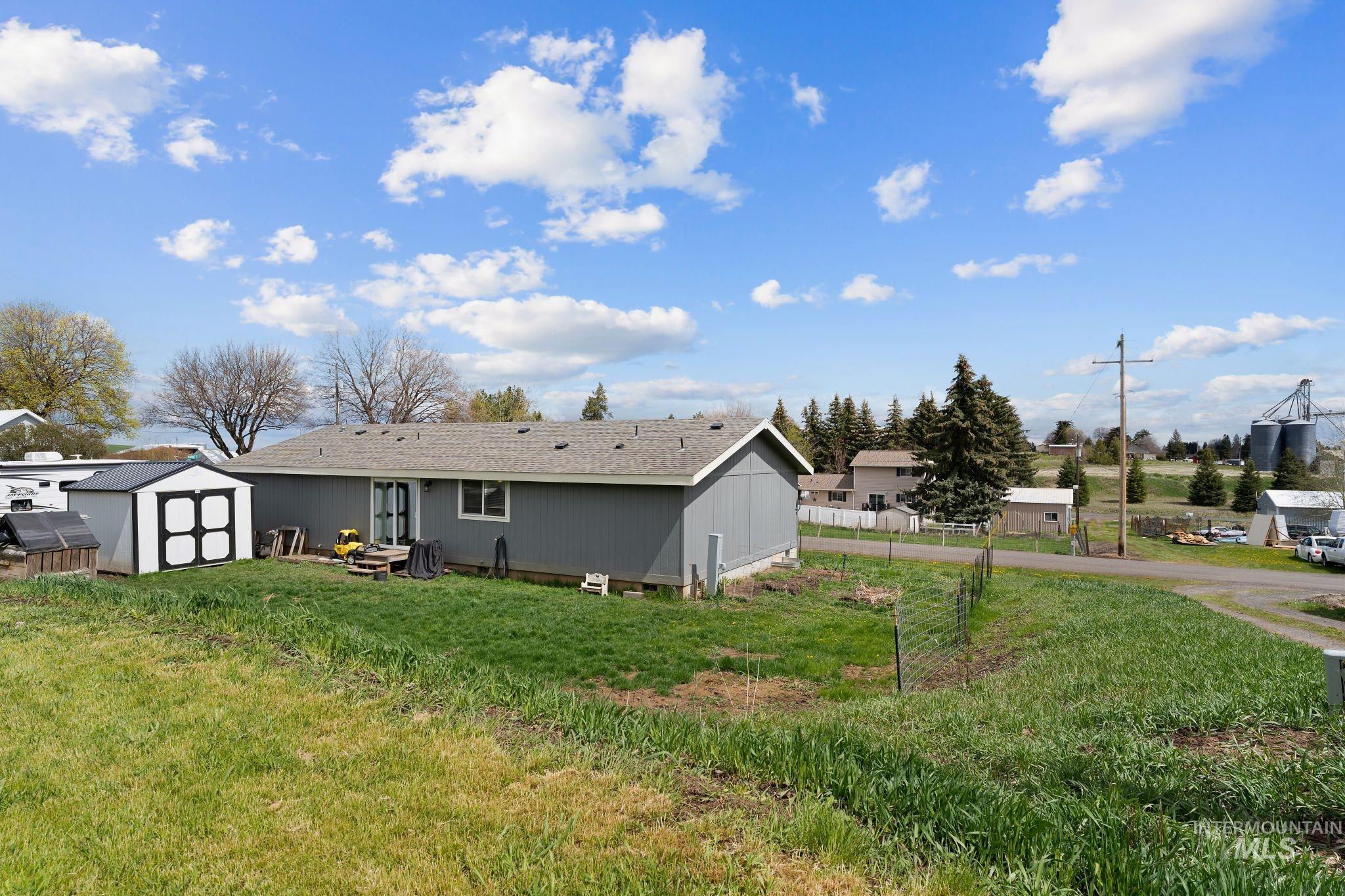 302 3rd Avenue Craigmont, ID 83523 - Photo 29 of 31 Rear exterior featuring gray siding, a light gray shingle roof, and a white-framed window