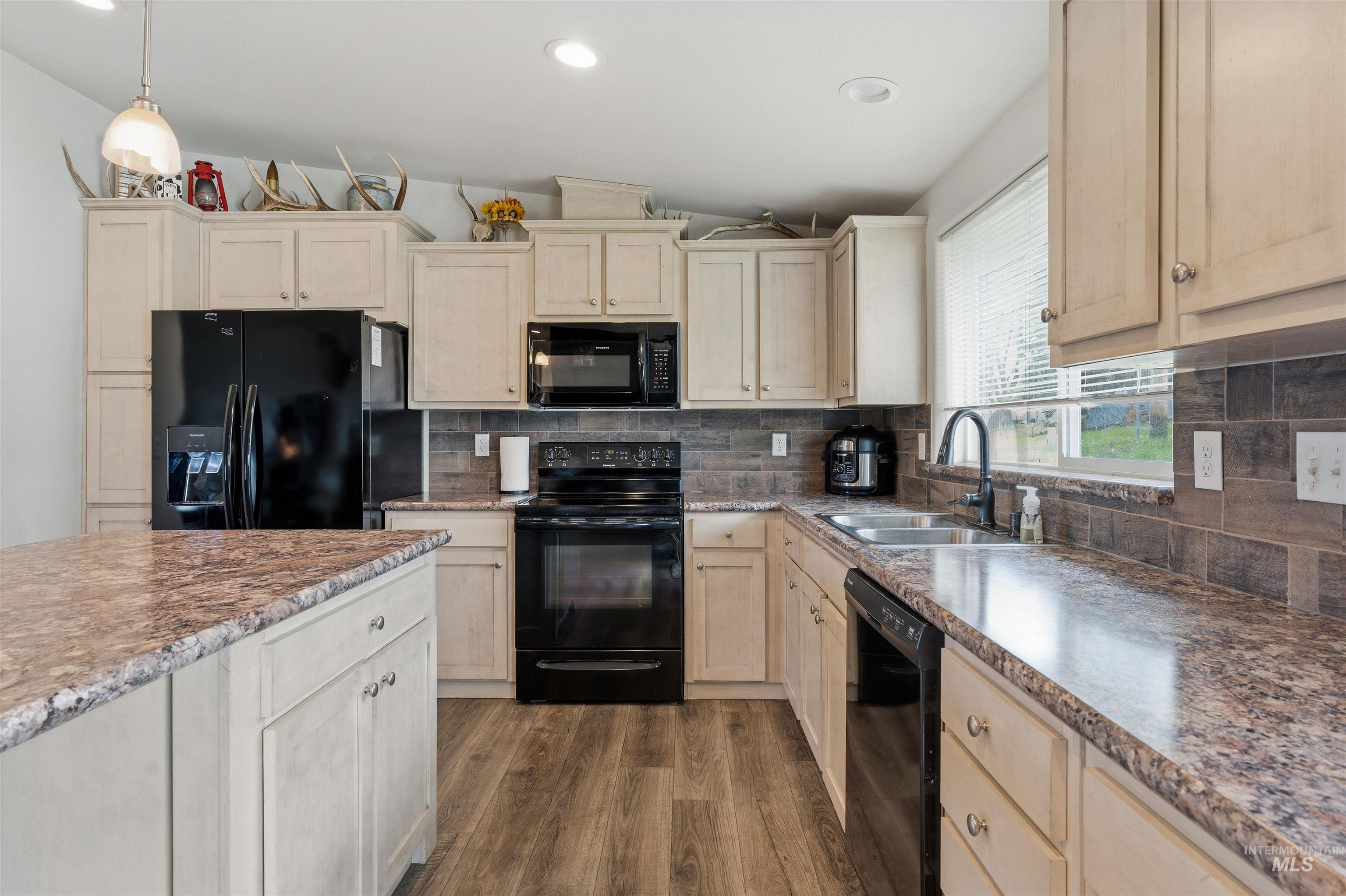 302 3rd Avenue Craigmont, ID 83523 - Photo 5 of 31 Kitchen featuring an island, light wood-finish cabinetry, black appliances, speckled countertops, and wood-finish flooring
