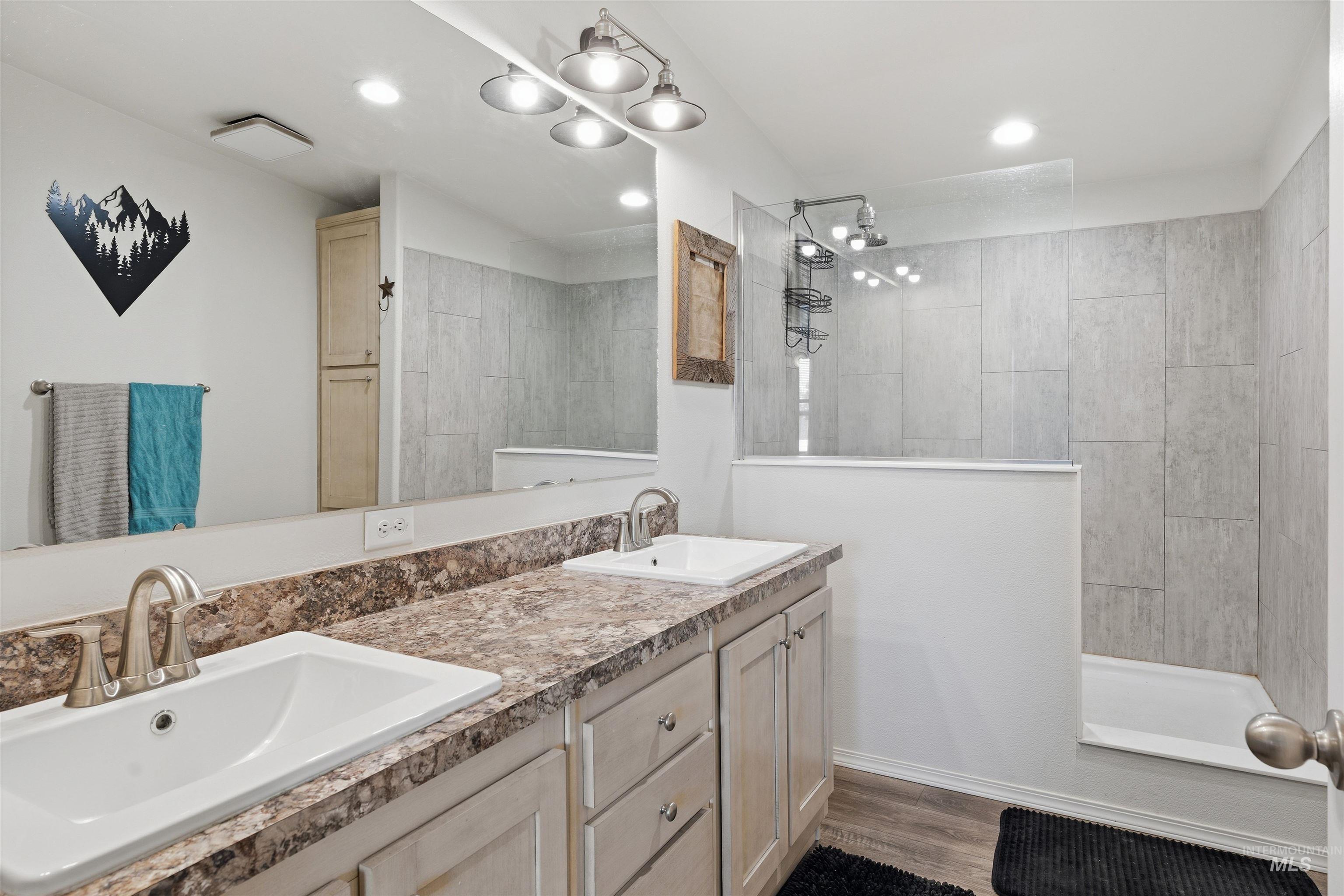 302 3rd Avenue Craigmont, ID 83523 - Photo 9 of 31 Bathroom featuring a dual vanity with undermount sinks, patterned countertops, and light wood-finish cabinetry