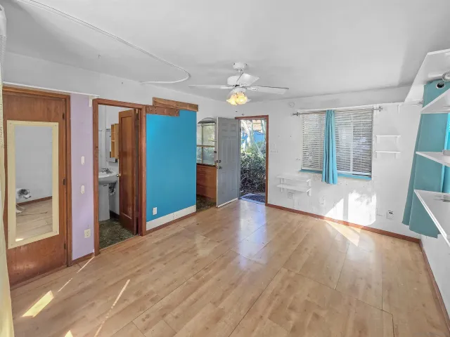 a view of an empty room with window and wooden floor