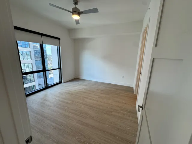 a view of a hallway with wooden floor and a bathroom