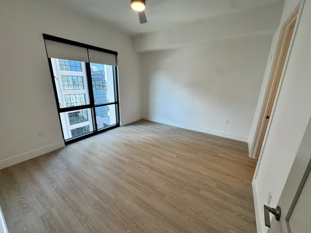an empty room with wooden floor closet and fan