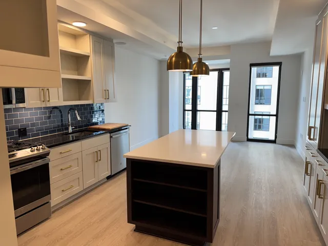 a large kitchen with stainless steel appliances granite countertop a stove and a wooden floors