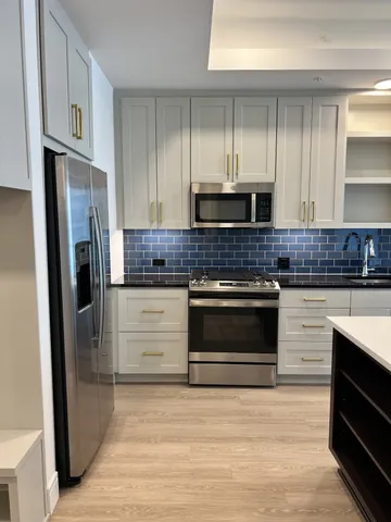 a large kitchen with a large window a sink and stainless steel appliances