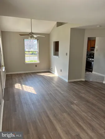 an empty room with wooden floor chandelier and windows