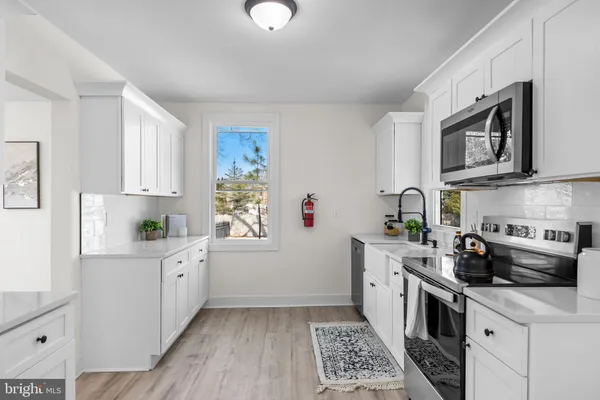 a kitchen with stainless steel appliances a sink a stove a microwave a refrigerator a cabinets and wooden floor