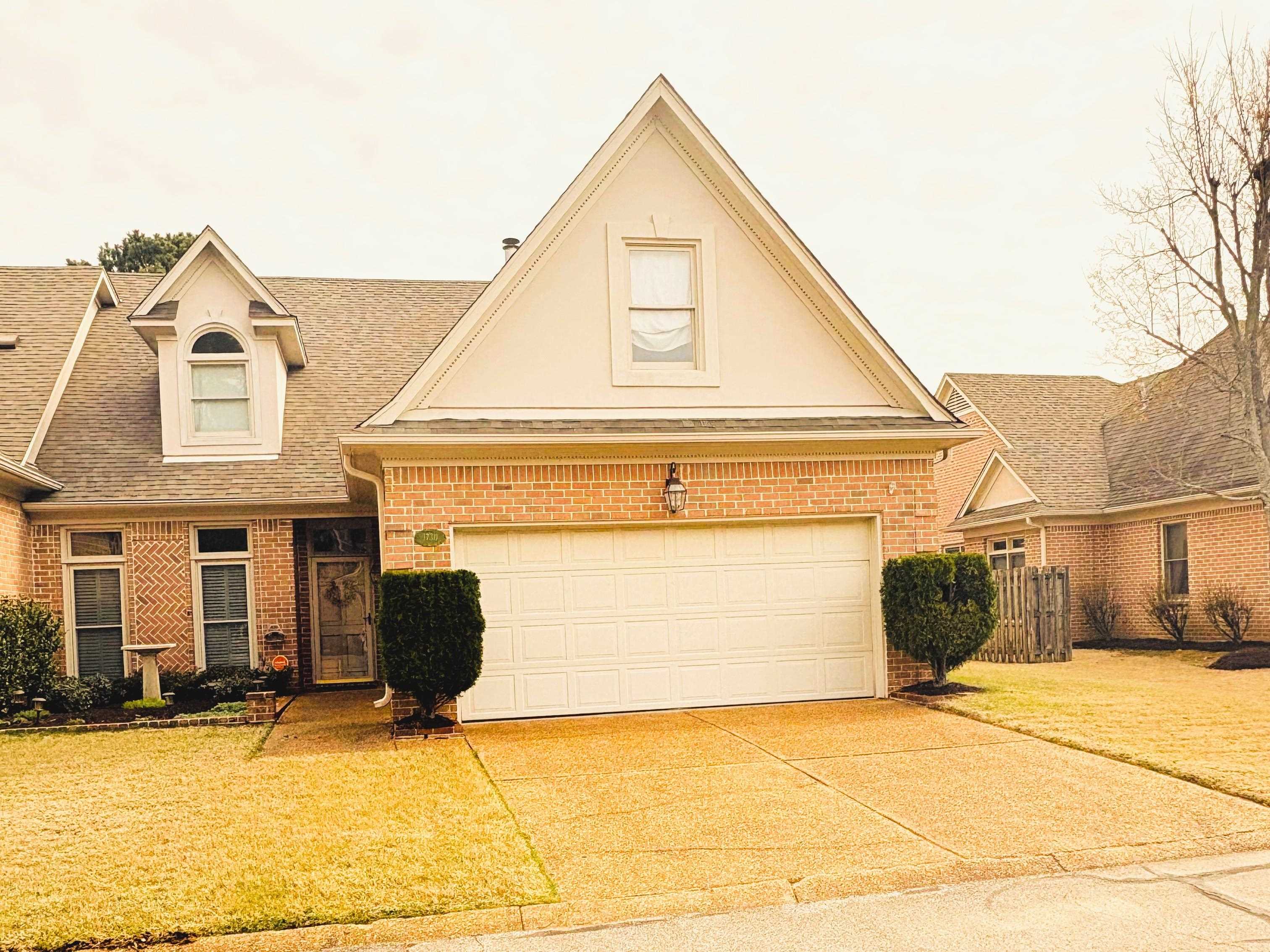 View of front of house featuring brick siding, roof with shingles, driveway, and a garage