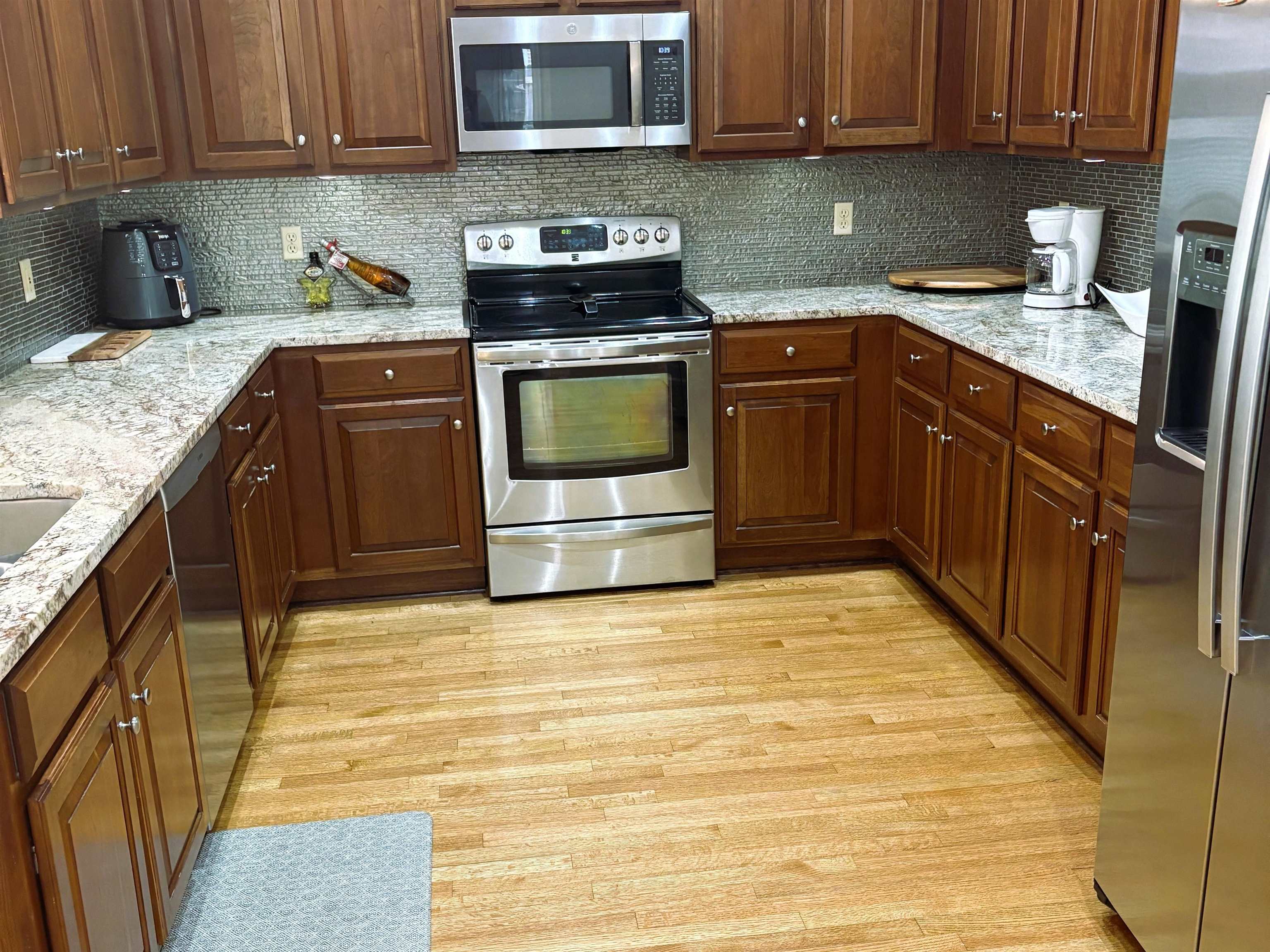 1730 Gosnold Bluff Road Collierville, TN 38017 - Photo 3 of 15 Kitchen with stainless steel appliances, decorative backsplash, light stone countertops, and light wood-style floors