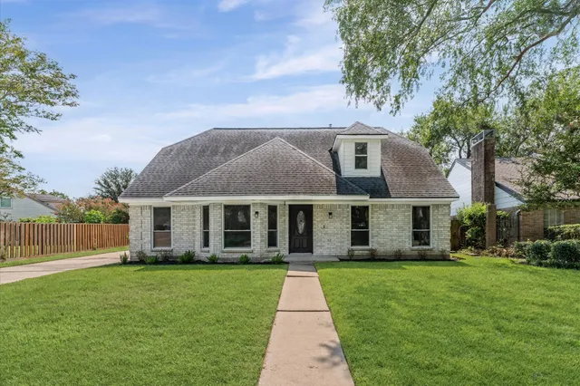 a front view of a house with a garden and trees