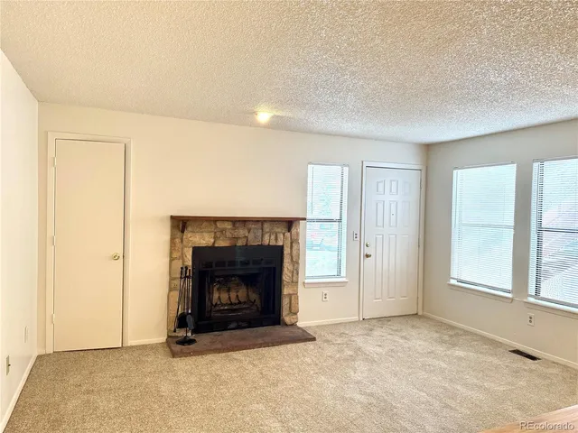 an empty room with windows and fireplace