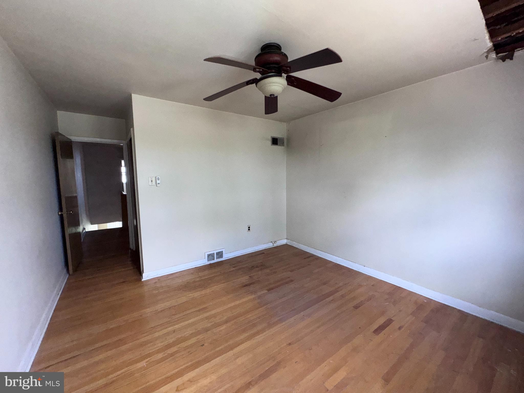 7448 Rhoads Street Philadelphia, PA 19151 - Photo 7 of 17 an empty room with wooden floor and a ceiling fan