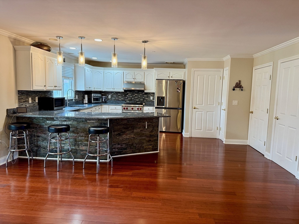 218 Rangeway Road, Unit 213 Billerica, MA 01862 - Photo 8 of 29 a kitchen with stainless steel appliances granite countertop a stove top oven a refrigerator a dining table and chairs with wooden floor