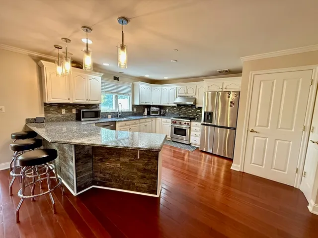 a kitchen with wooden floors white cabinets a sink and appliances