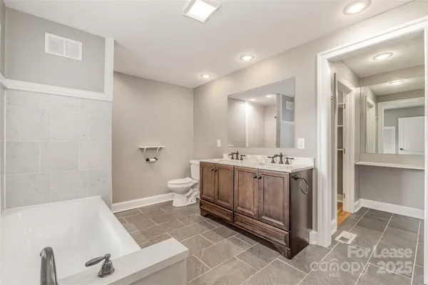 a spacious bathroom with a tub sink and mirror