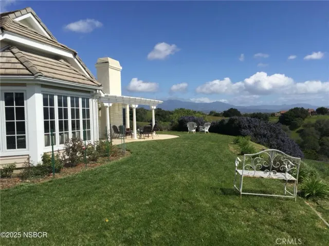 a garden with a bench in front of the house