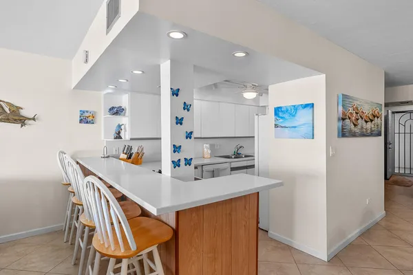 a kitchen with stainless steel appliances a sink a stove a refrigerator with white cabinets and wooden floor