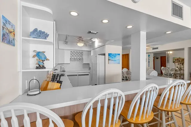 a kitchen with stainless steel appliances kitchen island granite countertop a sink and a refrigerator