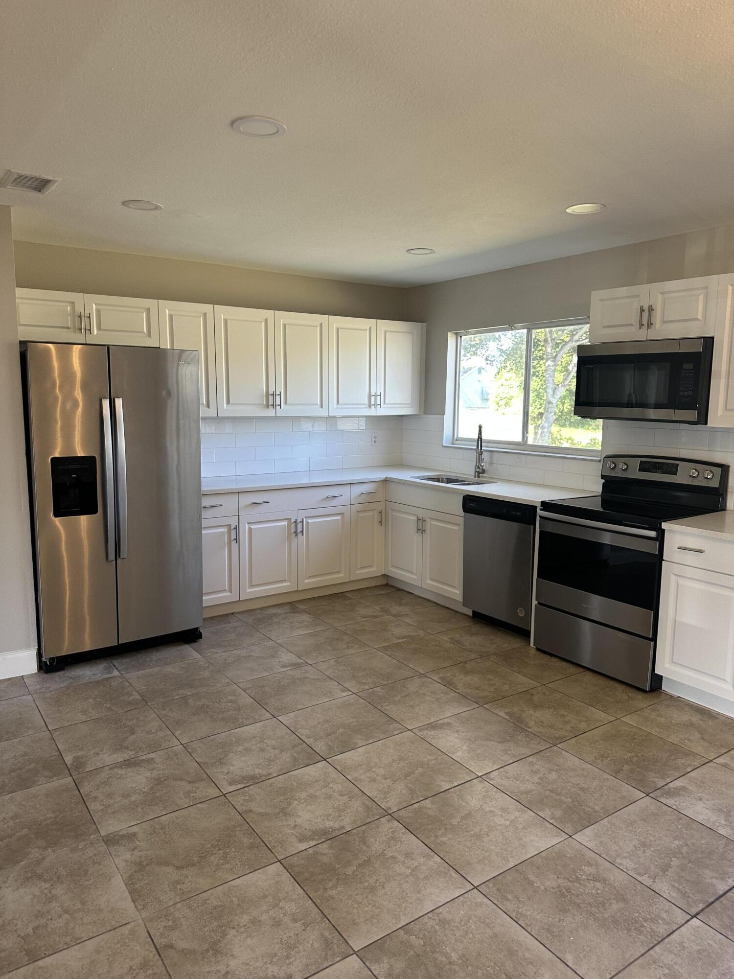 377 Southwest Cherryhill Road Port St. Lucie, FL 34953 - Photo 2 of 9 a kitchen with stainless steel appliances granite countertop a refrigerator and a sink