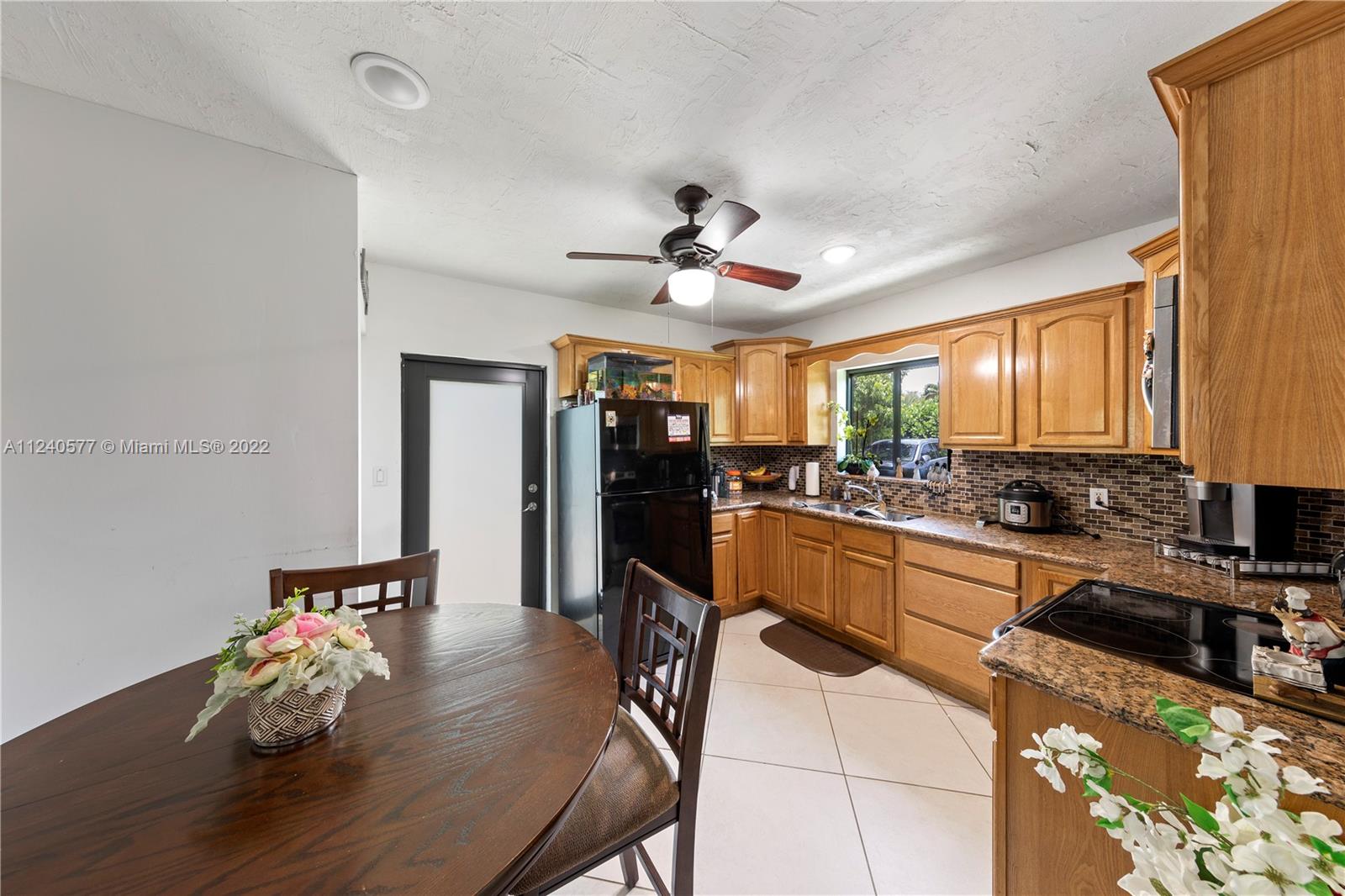 19760 Southwest 242nd Terrace Homestead, FL 33031 - Photo 28 of 49 a kitchen with stainless steel appliances kitchen island granite countertop a stove a refrigerator a sink a dining table and chairs with wooden floor