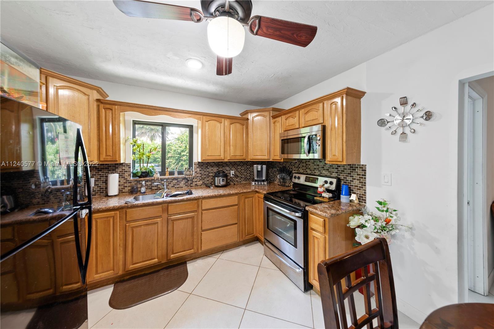 19760 Southwest 242nd Terrace Homestead, FL 33031 - Photo 30 of 49 a kitchen with stainless steel appliances granite countertop a stove top oven a sink a dining table and chairs with wooden floor