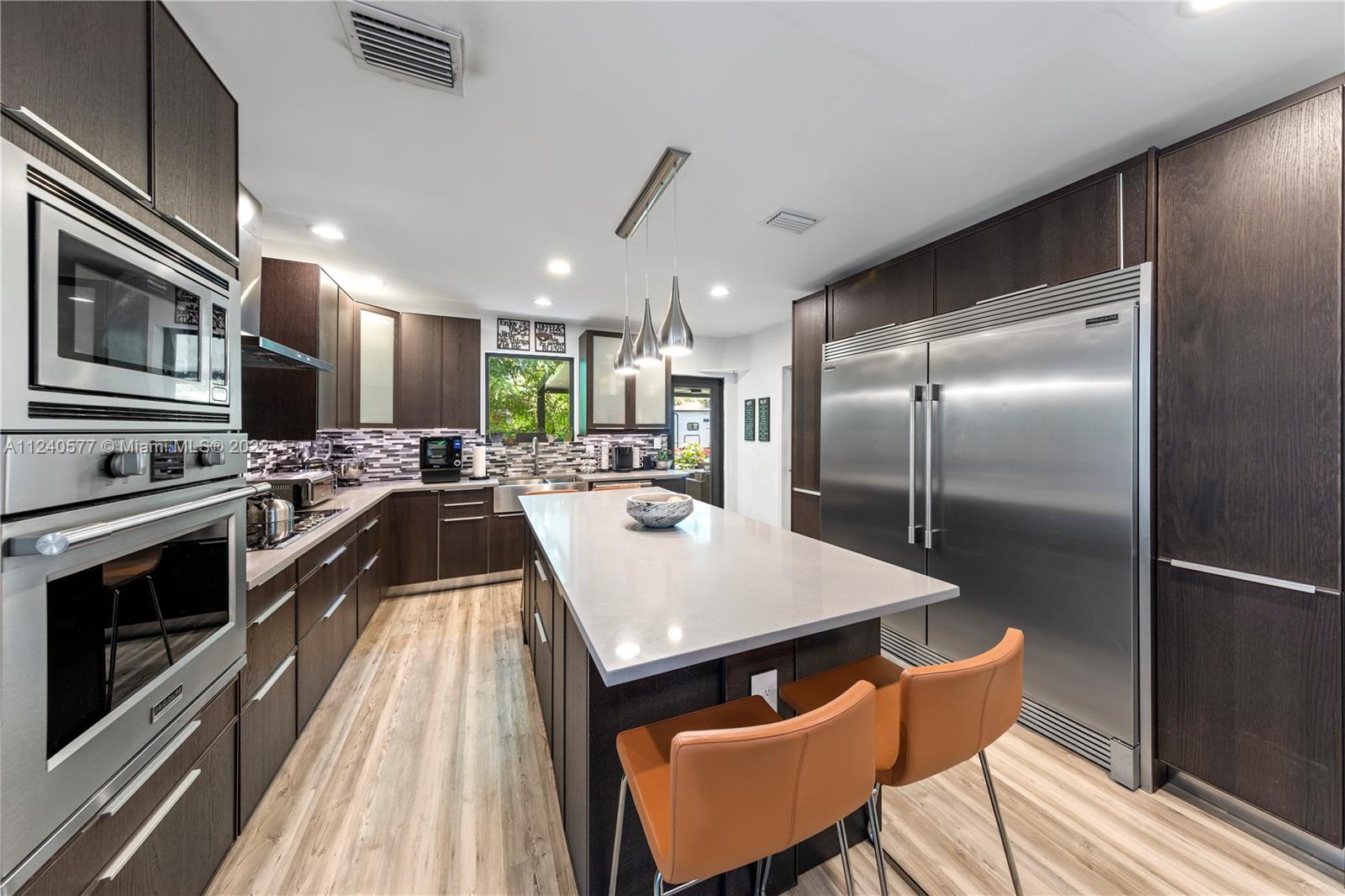 19760 Southwest 242nd Terrace Homestead, FL 33031 - Photo 10 of 49 a large kitchen with stainless steel appliances kitchen island granite countertop a large kitchen island a stove a refrigerator with a dining table and chairs with wooden floor