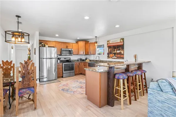 a kitchen with stainless steel appliances granite countertop a sink a stove and a wooden floors