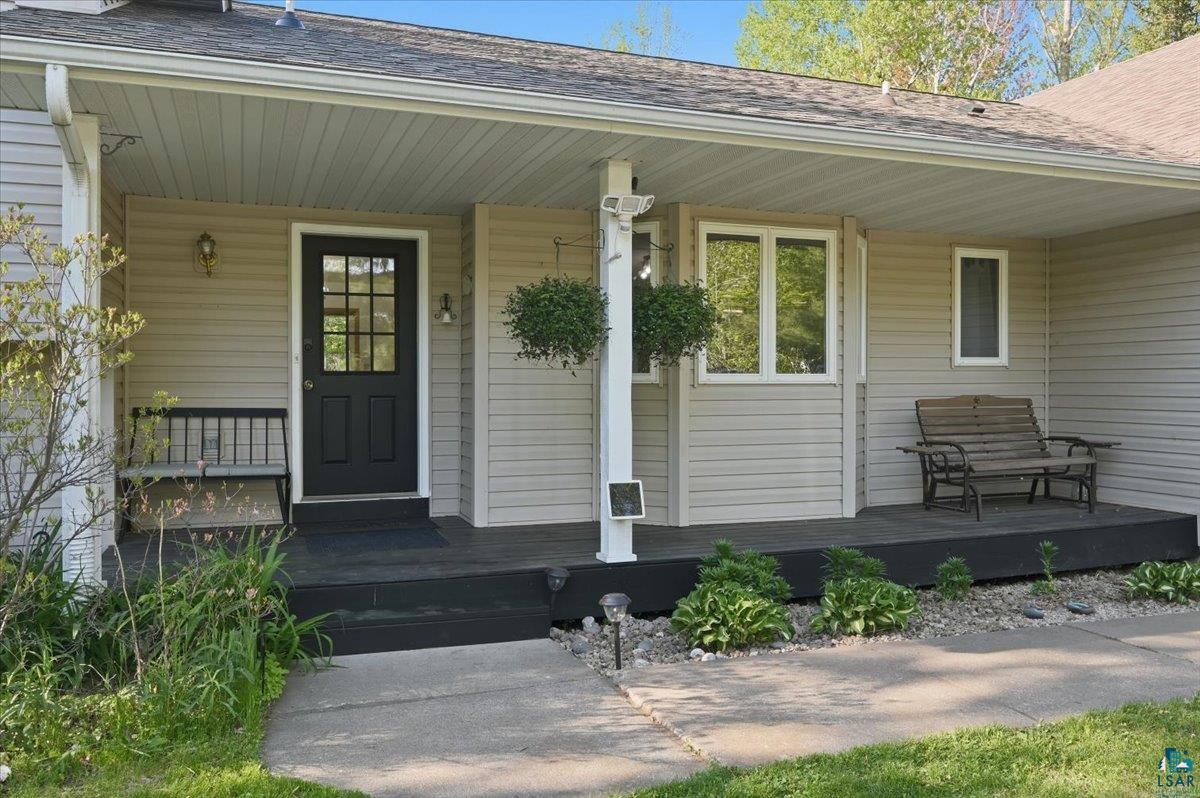 47 Amy Lane Esko, MN 55733 - Photo 3 of 33 Covered front porch featuring neutral siding, a dark paneled door with windowpanes, white trim, and a concrete walkway