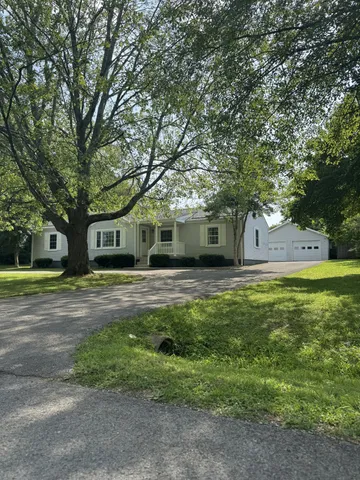 a front view of a house with a garden and trees