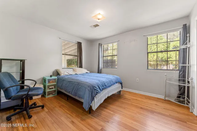 a spacious bedroom with a bed and wooden floor