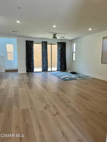 a view of an empty room with window and wooden floor