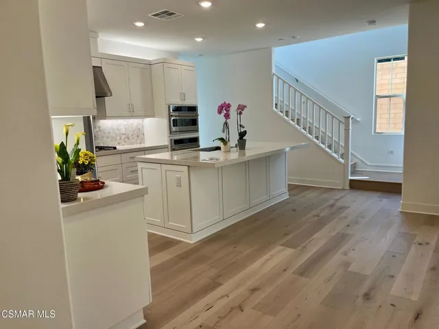 a kitchen with stainless steel appliances a white stove top oven and a wooden floor
