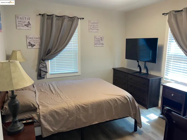 a bedroom with a bed and a flat tv screen on the dresser