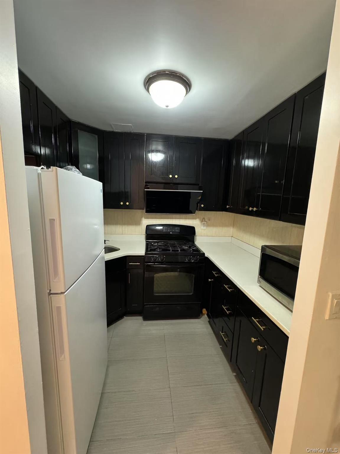 38-08 147th Street, Unit C2 Queens, NY 11357 - Photo 3 of 12 a kitchen with a refrigerator and a stove top oven