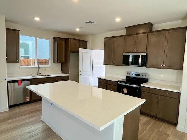 a kitchen with stainless steel appliances a stove a sink a microwave a refrigerator a stove and cabinets