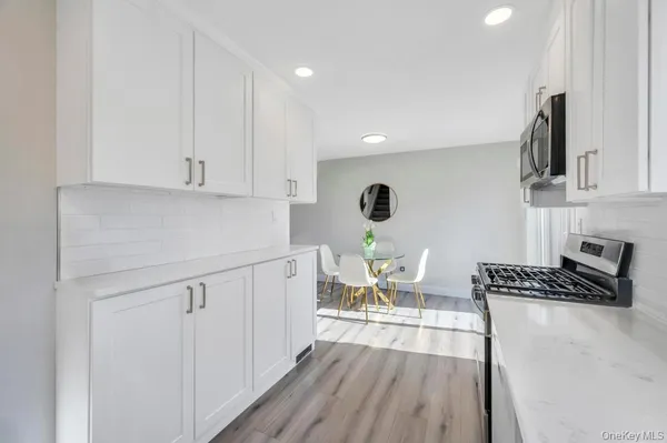 a kitchen with a sink a stove and white cabinets with wooden floor
