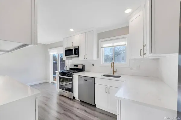 a kitchen with white cabinets sink and stainless steel appliances