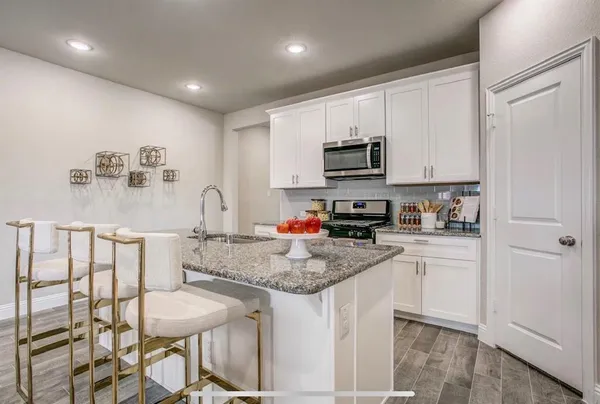 a kitchen with stainless steel appliances granite countertop a sink a stove a microwave a refrigerator and cabinets