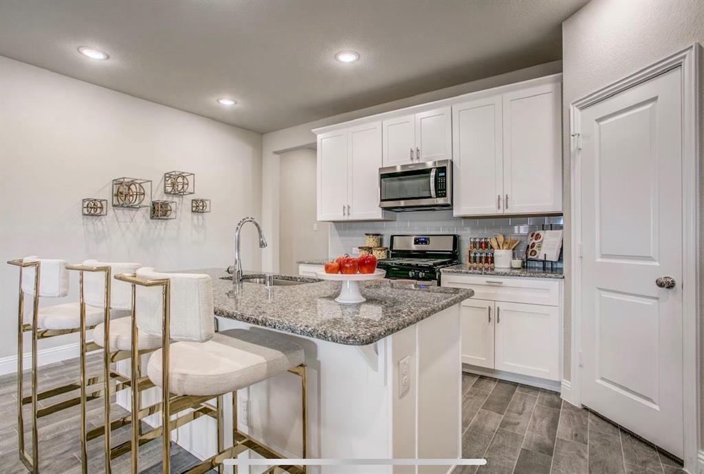 4432 Thalia Way Forney, TX 75126 - Photo 5 of 16 a kitchen with stainless steel appliances granite countertop a sink a stove a microwave a refrigerator and cabinets