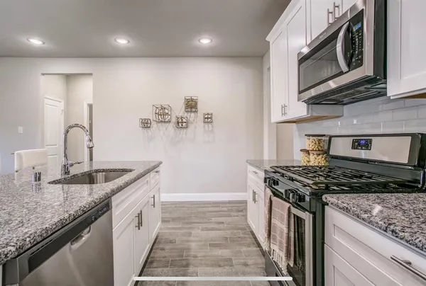 a kitchen with stainless steel appliances granite countertop a sink stove and cabinets