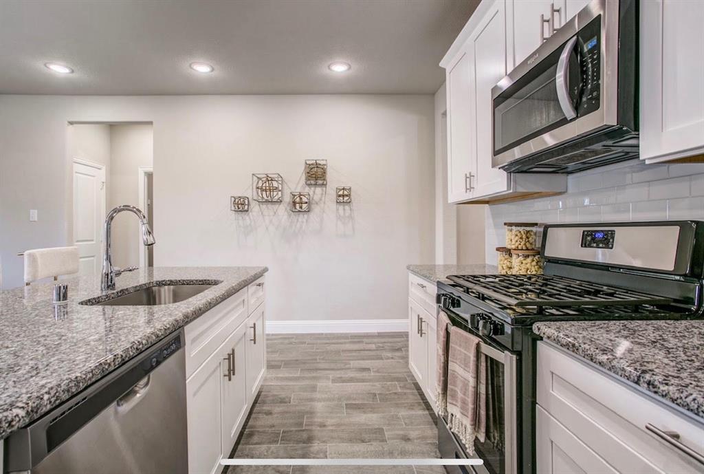 4432 Thalia Way Forney, TX 75126 - Photo 6 of 16 a kitchen with stainless steel appliances granite countertop a sink stove and cabinets