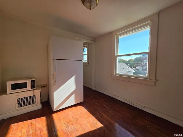 a view of an empty room with wooden floor and windows