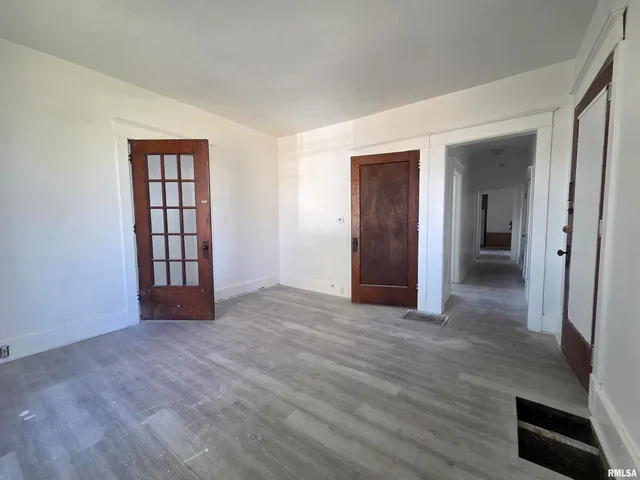 a view of an empty room with wooden floor and closet